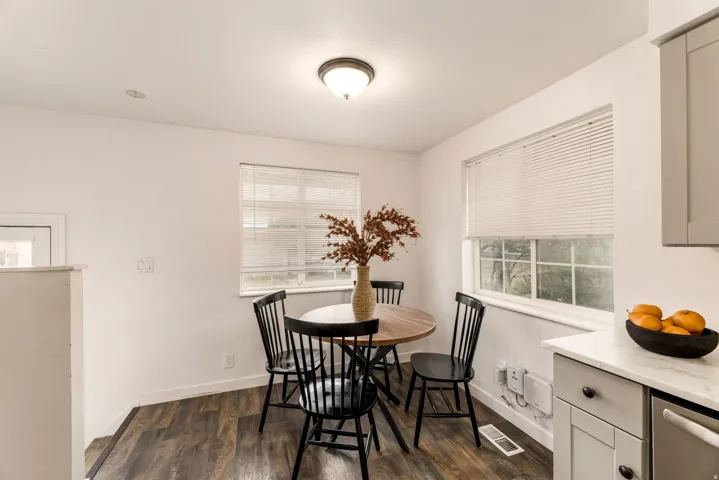 Light-filled dining area featuring wood-finish flooring, two large windows with blinds, and recessed lighting