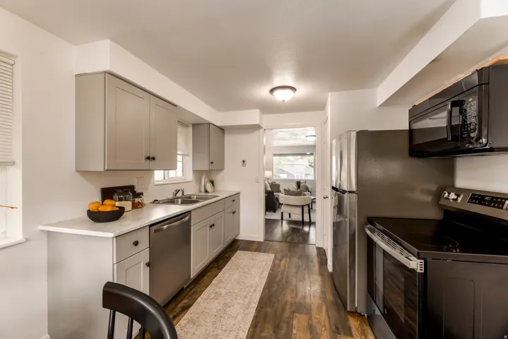 Kitchen featuring light gray cabinetry, stainless steel appliances, a double basin sink, and wood-finish flooring