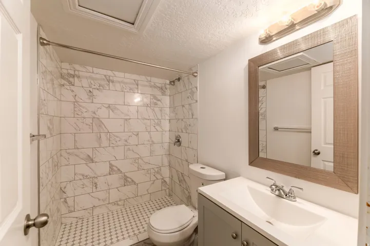 Bathroom featuring a vanity with a white integrated sink, chrome faucet, and gray cabinetry