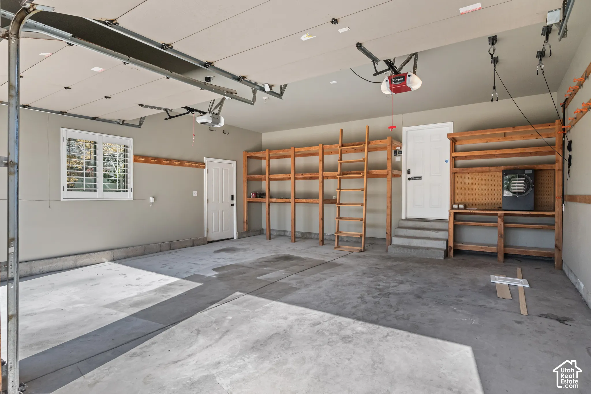 Spacious 2-car garage featuring a concrete floor, built-in wooden shelving, and two automatic garage door openers