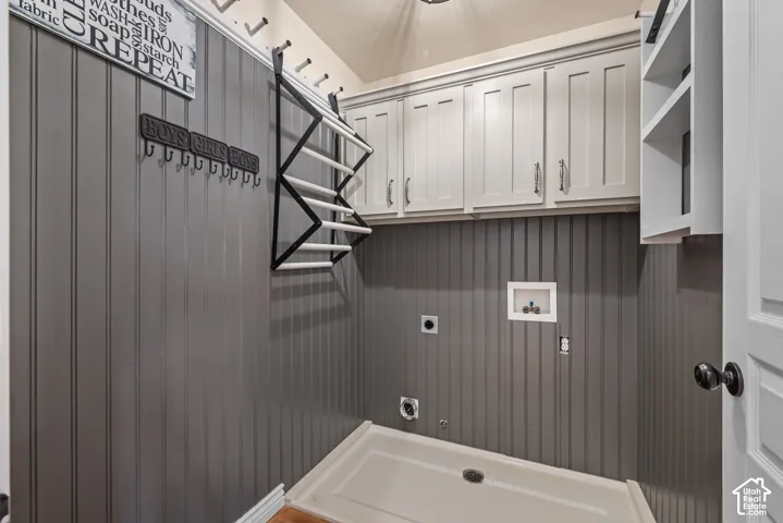 Dedicated utility room with upper cabinetry, beadboard wainscoting, and a built-in washer drain tray.