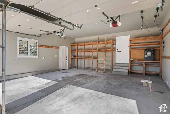 Spacious 2-car garage featuring a concrete floor, built-in wooden shelving, and two automatic garage door openers