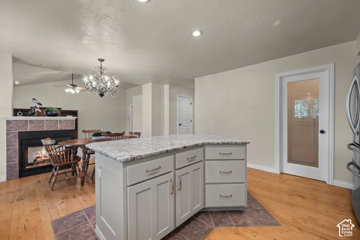 Kitchen island with light-toned cabinetry, granite countertop, lots of storage