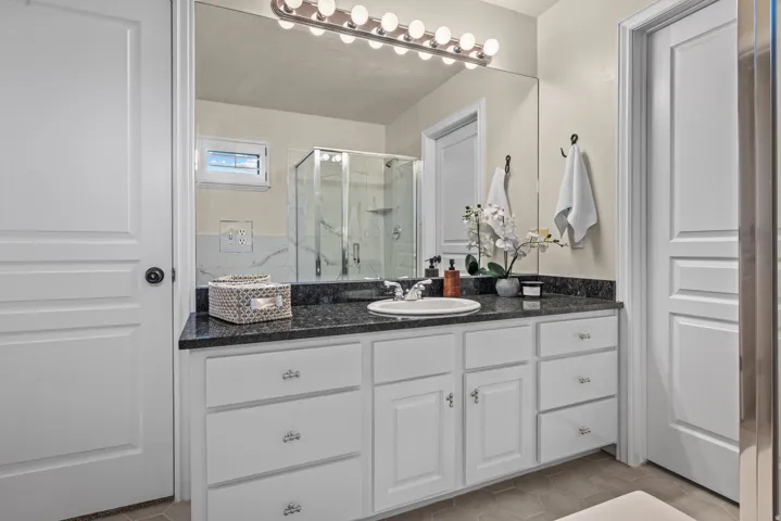 Primary bathroom vanity with single sink and granite countertop