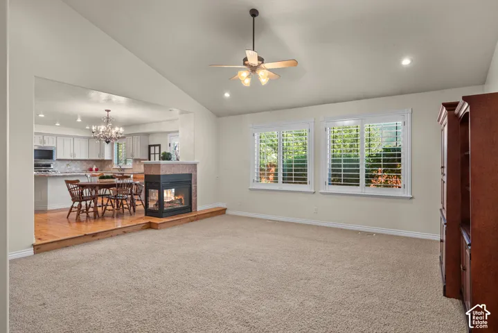 Inviting great room with vaulted ceiling with a ceiling fan, recessed lighting, and a 2-way fireplace