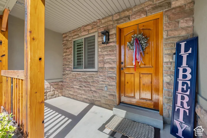 Inviting front entry featuring a natural wood door, stone facade, and a covered porch with wood columns
