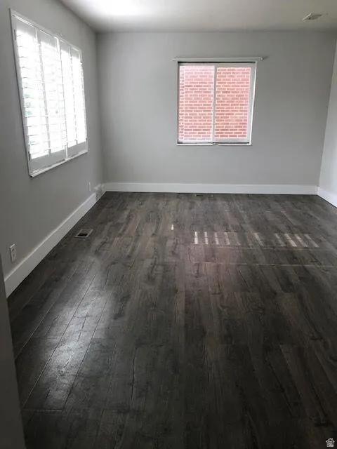 Spacious room with dark wood-finish flooring and white baseboards