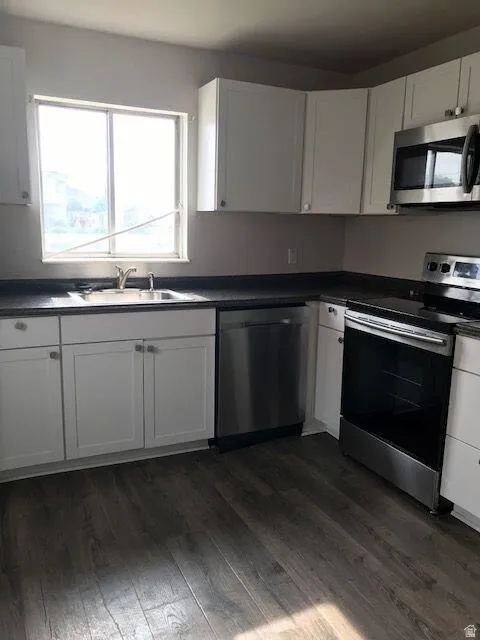 Kitchen with white cabinetry, dark countertops, and wood-finish flooring