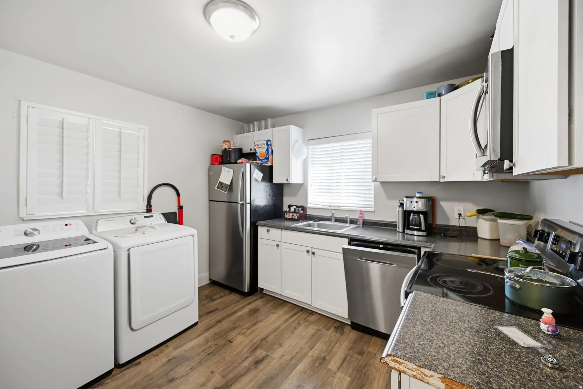 Kitchen featuring wood-finish flooring, white cabinetry, dark countertops, and stainless steel appliances