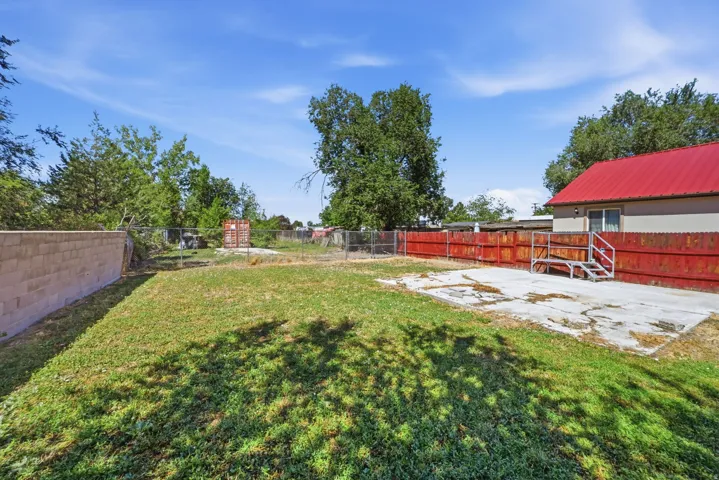 Backyard space featuring a concrete patio area, a wood fence, and mature trees