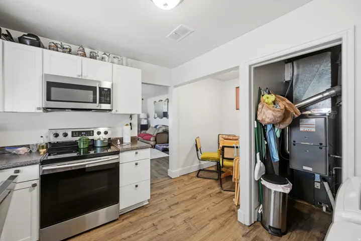 Kitchen featuring white cabinetry, stainless steel microwave, stainless steel range, and wood-finish flooring