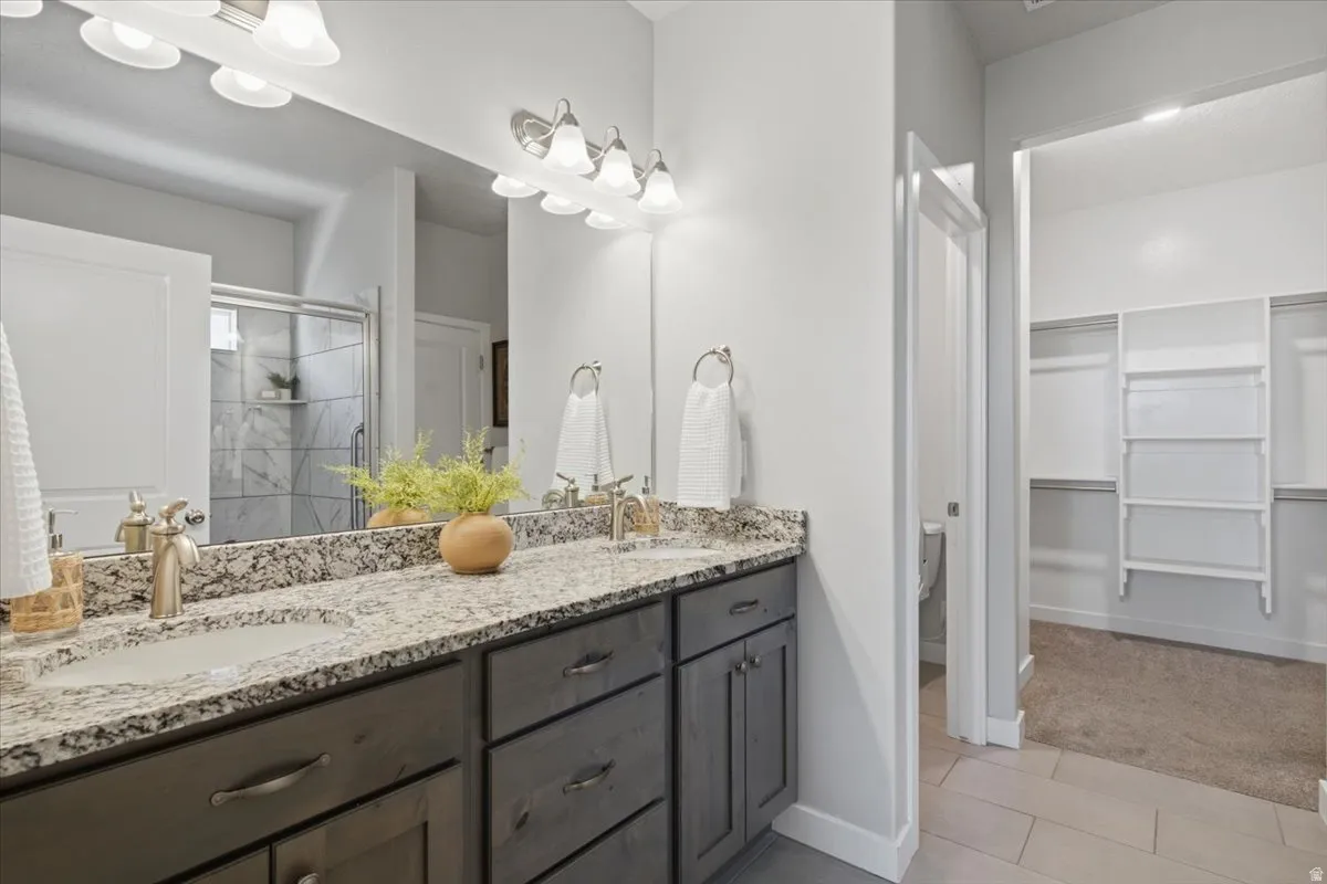 Bathroom vanity featuring dual undermount sinks with brushed nickel fixtures, granite countertop, and dark wood-finish cabinetry