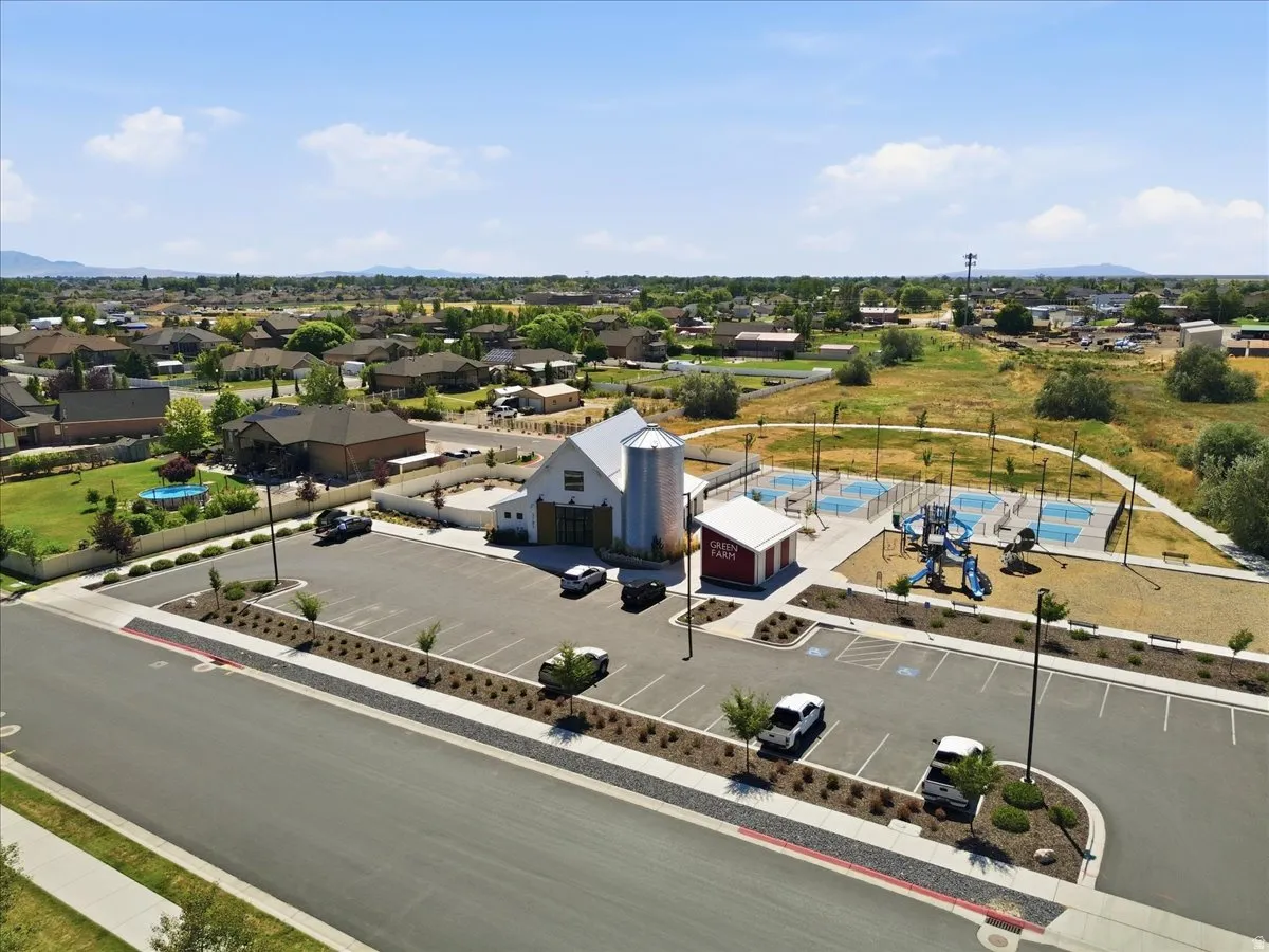 Community amenity area featuring a modern barn-style building, an adjacent grain silo structure, multiple pickleball courts, a playground, and ample surface parking