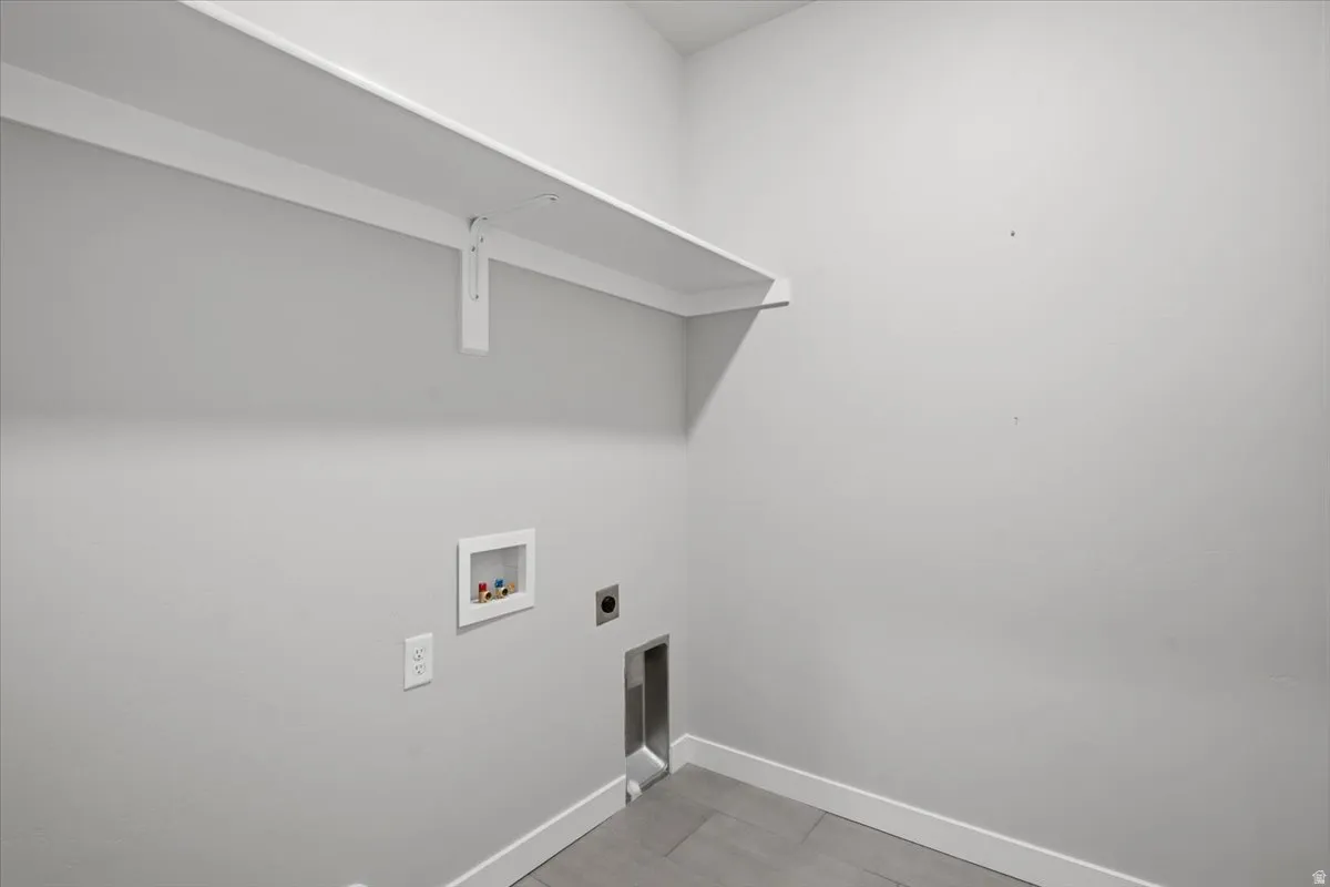 Dedicated laundry space featuring a white wall shelf, light gray walls, and wood-finish flooring