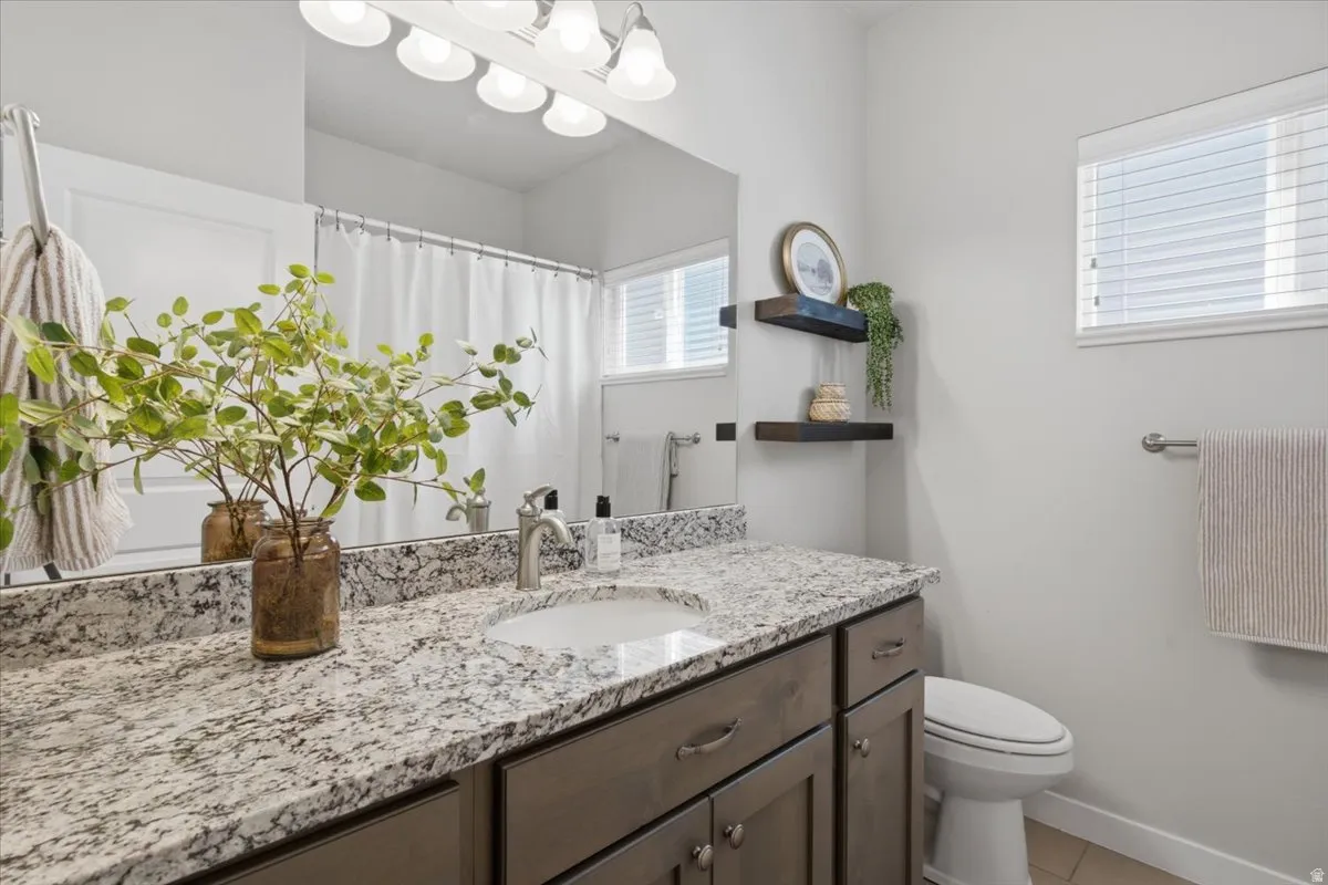 Bathroom featuring a vanity with a white-patterned countertop, an undermount sink, and a brushed nickel faucet