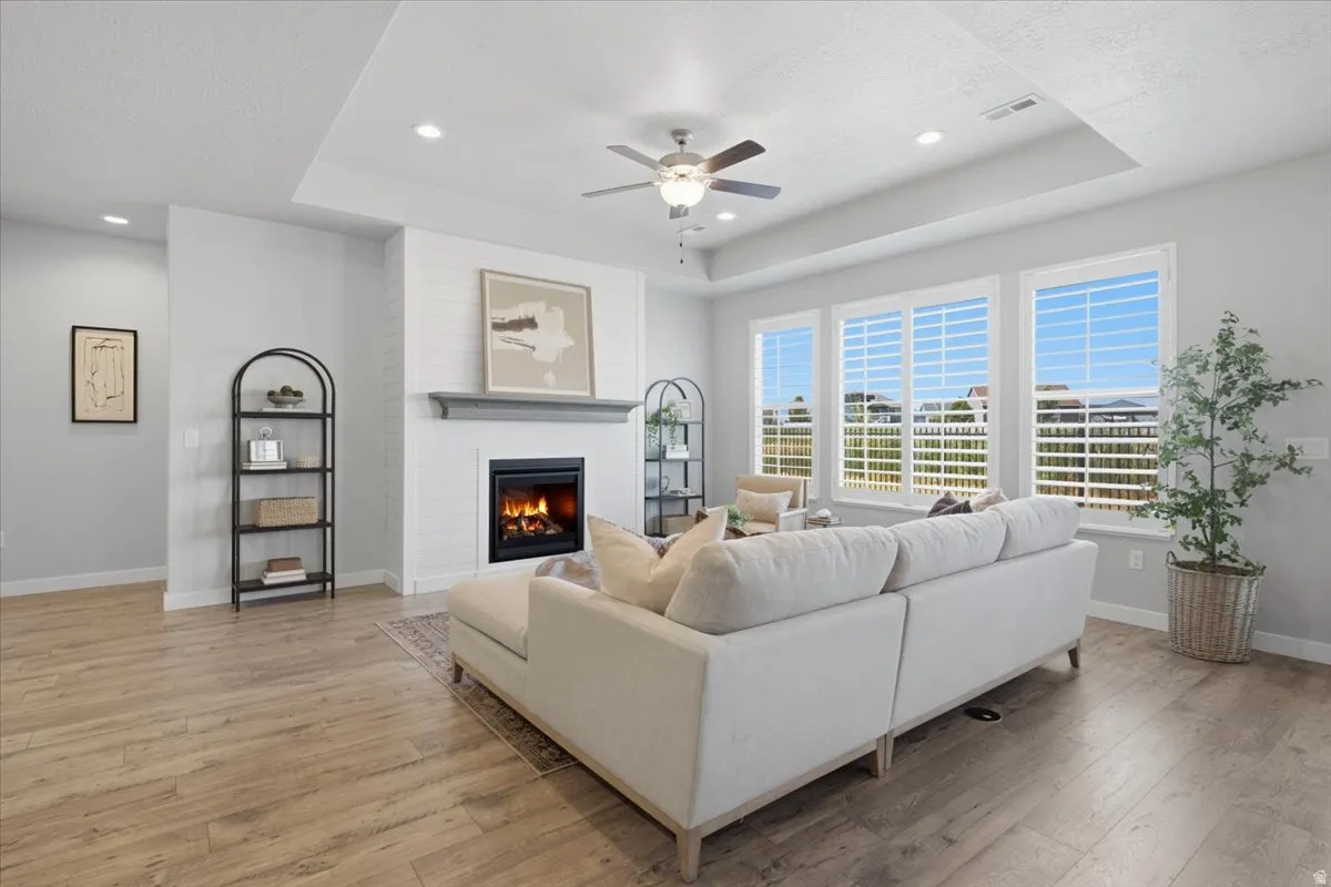 Living room featuring a fireplace with shiplap surround, a wood mantel, and a tray ceiling