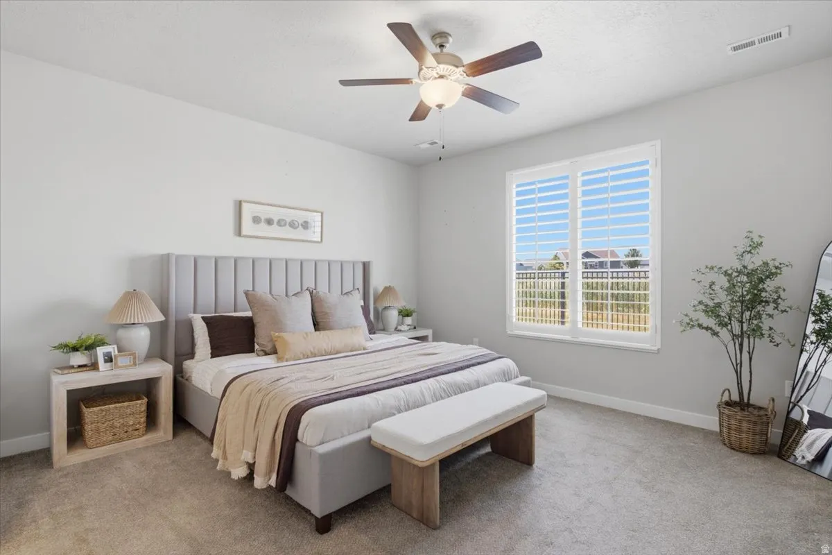Bright room featuring a large window with white plantation shutters, neutral carpeting, and a ceiling fan with integrated lighting