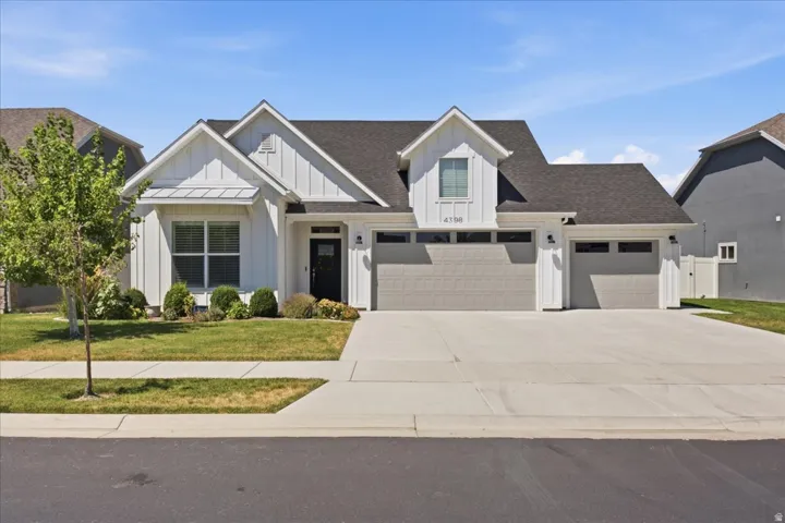 Contemporary ranch-style exterior featuring white board and batten siding, dark shingle roofing, and a prominent three-car garage