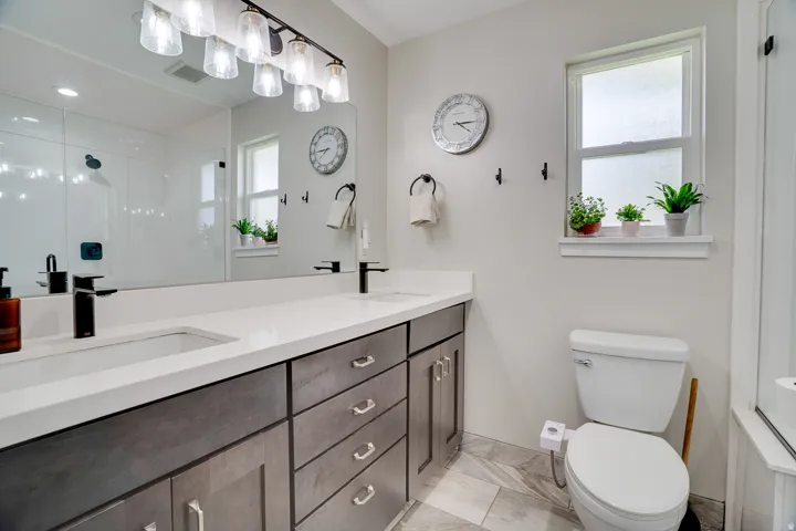 Bathroom featuring a dual vanity with white countertops, dark wood-finish cabinetry, and matte black fixtures