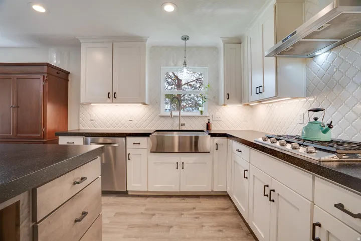 Chef's kitchen featuring crisp white cabinetry with brushed nickel hardware, quartz countertops, a farmhouse-style apron-front sink with polished stainless steel fixtures, and professional-grade gas cooktop
