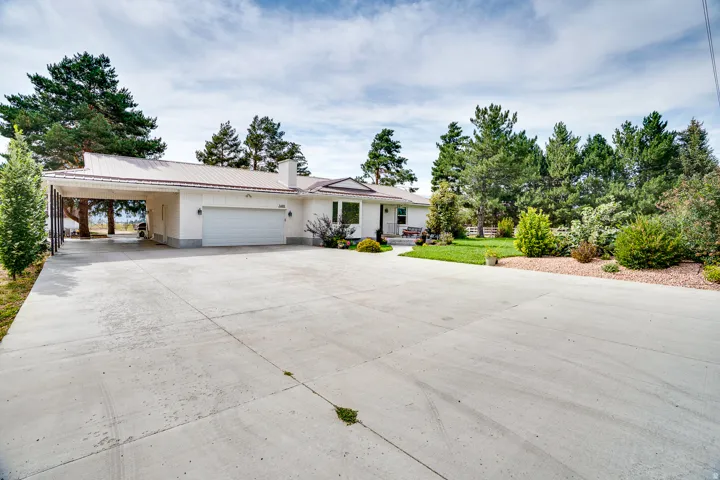 Single-story residence featuring a metal roof, attached carport, two-car garage, and a concrete driveway