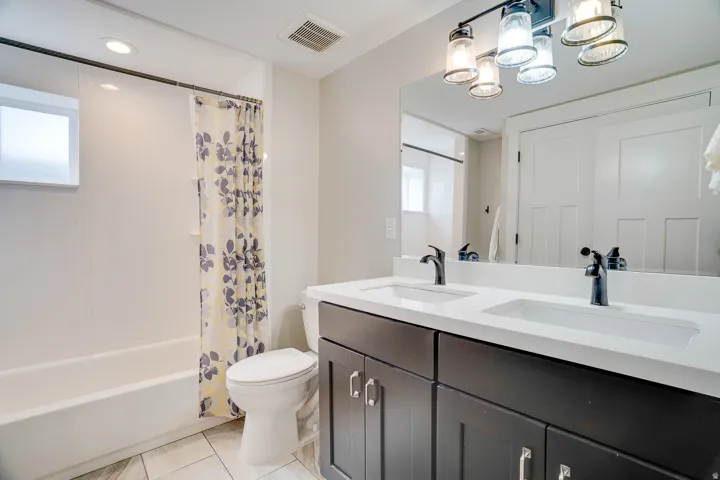 Dual sink vanity with dark cabinetry, white countertops, and matte black fixtures
