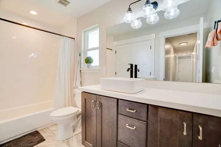 Bathroom featuring a modern vanity with a vessel sink, quartz countertop, and dark wood cabinetry