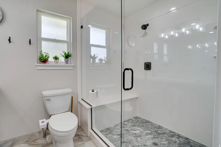 Glass-enclosed shower featuring a built-in bench and dark-toned floor tile