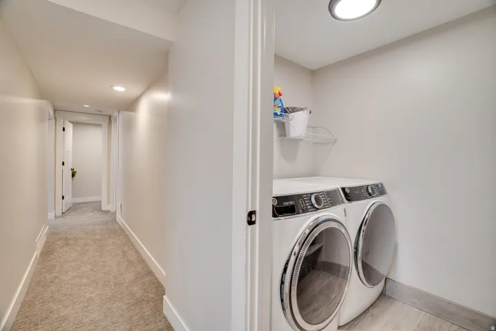 Dedicated laundry area featuring a front-loading washer and dryer, recessed lighting, and wood-finish flooring