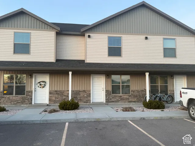 Two-story exterior with light beige horizontal siding and stacked stone veneer accents