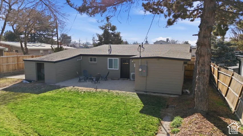 Expansive backyard featuring a manicured lawn, a large patio area, a detached storage building, a multi-panel wooden fence, and mature trees