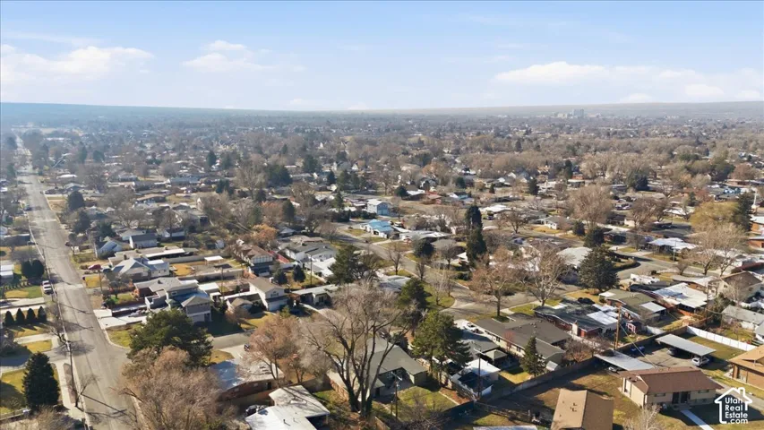 Expansive neighborhood setting featuring a mix of residential properties, tree-lined streets, and a discernible urban skyline in the distance