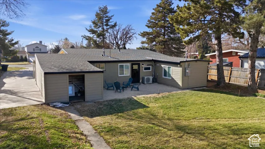Backyard featuring an expansive lawn, concrete patio, and a separate storage structure
