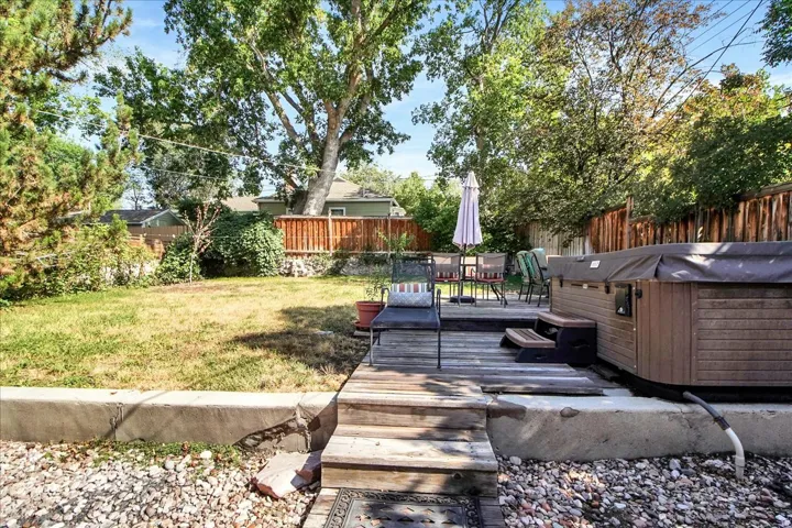 Backyard featuring a multi-level wood deck, an integrated hot tub, and a spacious lawn area