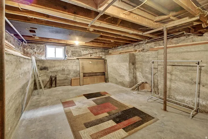 Unfinished basement with concrete flooring and exposed wooden ceiling joists