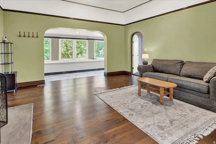 Spacious interior featuring rich wood-finish flooring and a wide arched opening to a sunroom