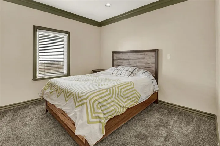Bedroom 1 featuring plush gray carpeting, a window with horizontal blinds, and recessed lighting