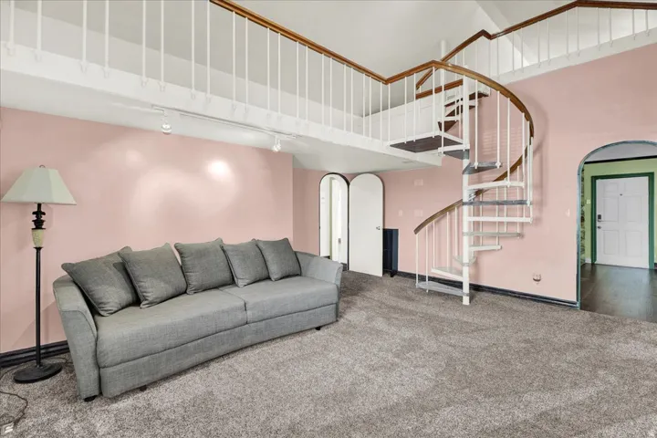 Bedroom 2 Living area featuring a spiral staircase with wood-finish handrails and white balusters, a carpeted floor, and a loft with a white railing