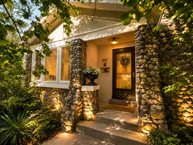 Stone-clad exterior featuring a prominent entry with a dark-framed glass-paneled door.  Virtually Enhanced