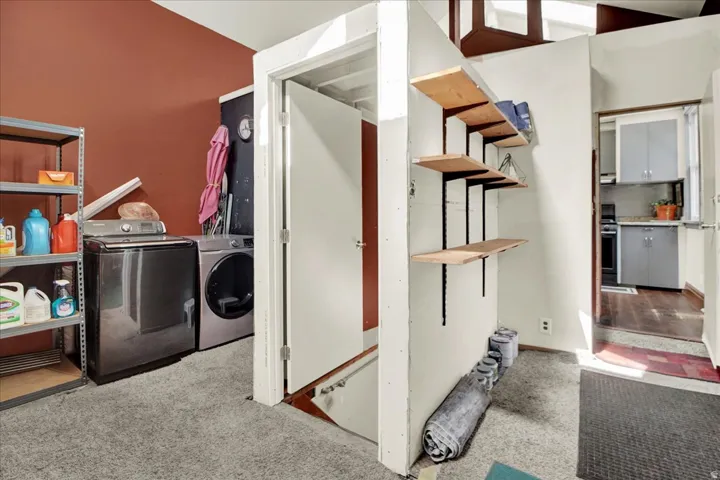 Dedicated laundry area featuring modern appliances and a rust-colored accent wall