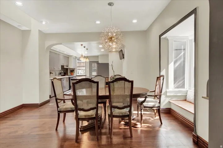 Spacious dining area featuring wood-finish flooring, recessed lighting, and a prominent decorative chandelier