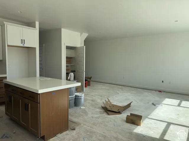 Kitchen island with light-toned countertop, built-in cabinetry, and integrated storage
