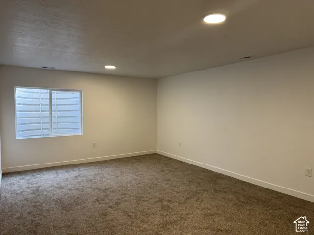 Neutral tone painted walls, recessed lighting, wall-to-wall carpeting, and a white-framed window
