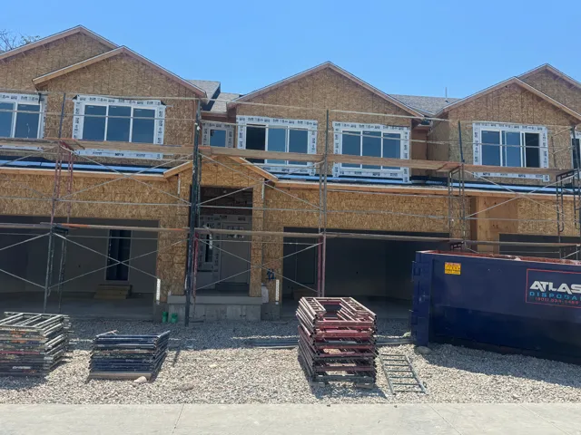 New construction townhome exteriors featuring multiple windows, attached garages, and pitched shingle roofs
