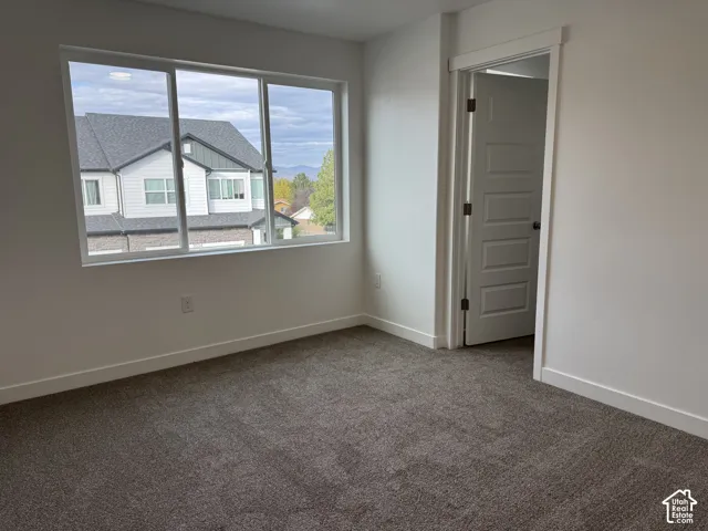 Room featuring neutral wall-to-wall carpeting, a large picture window, and a multi-panel interior door