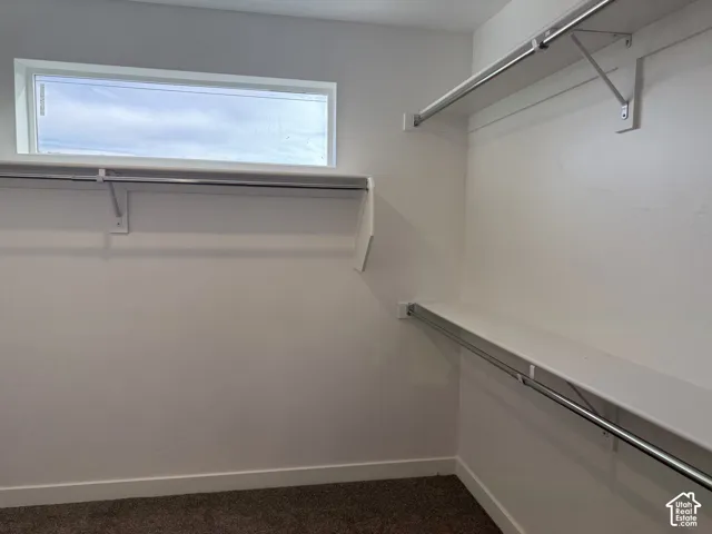 Built-in shelving and hanging rods, high-set rectangular window, white wall finish, and dark-toned carpeting