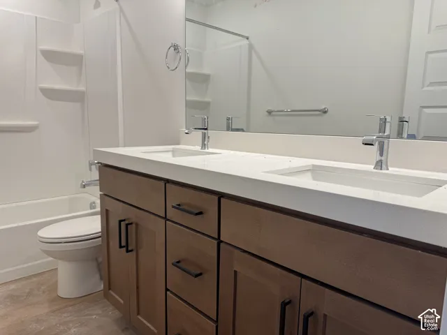 Double vanity with integrated sinks and chrome fixtures, white countertop, and wood-finish cabinetry with matte black hardware