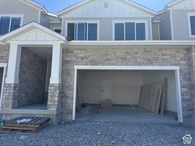 Stone veneer façade with siding accents, covered entry, and integrated garage