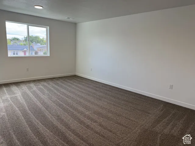 Neutral-toned interior space featuring neutral wall-to-wall carpeting, crisp white walls, and a recessed ceiling light fixture