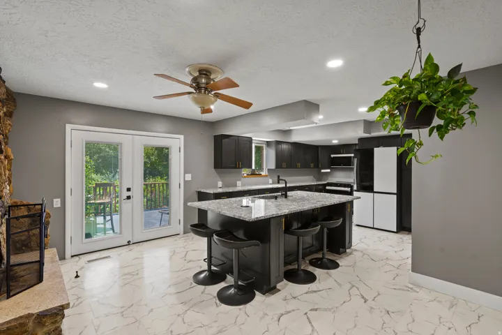 Kitchen featuring a large island with seating, dark cabinetry, and white marble-look flooring